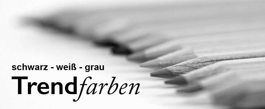 Aufgereihte Bunststifte schwarz eingefärbt davor Text schwarz weiß grau Trendfarben (Bildmontage)