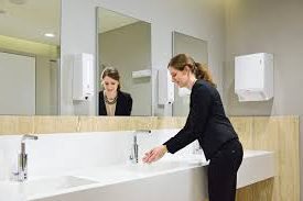 Frau wäscht sich im Waschraum im Handwaschbecken die Hände