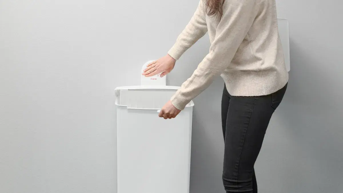 Frau bei der Bedienung einer Berührunslosen CWS-Hygienebox wandhängend